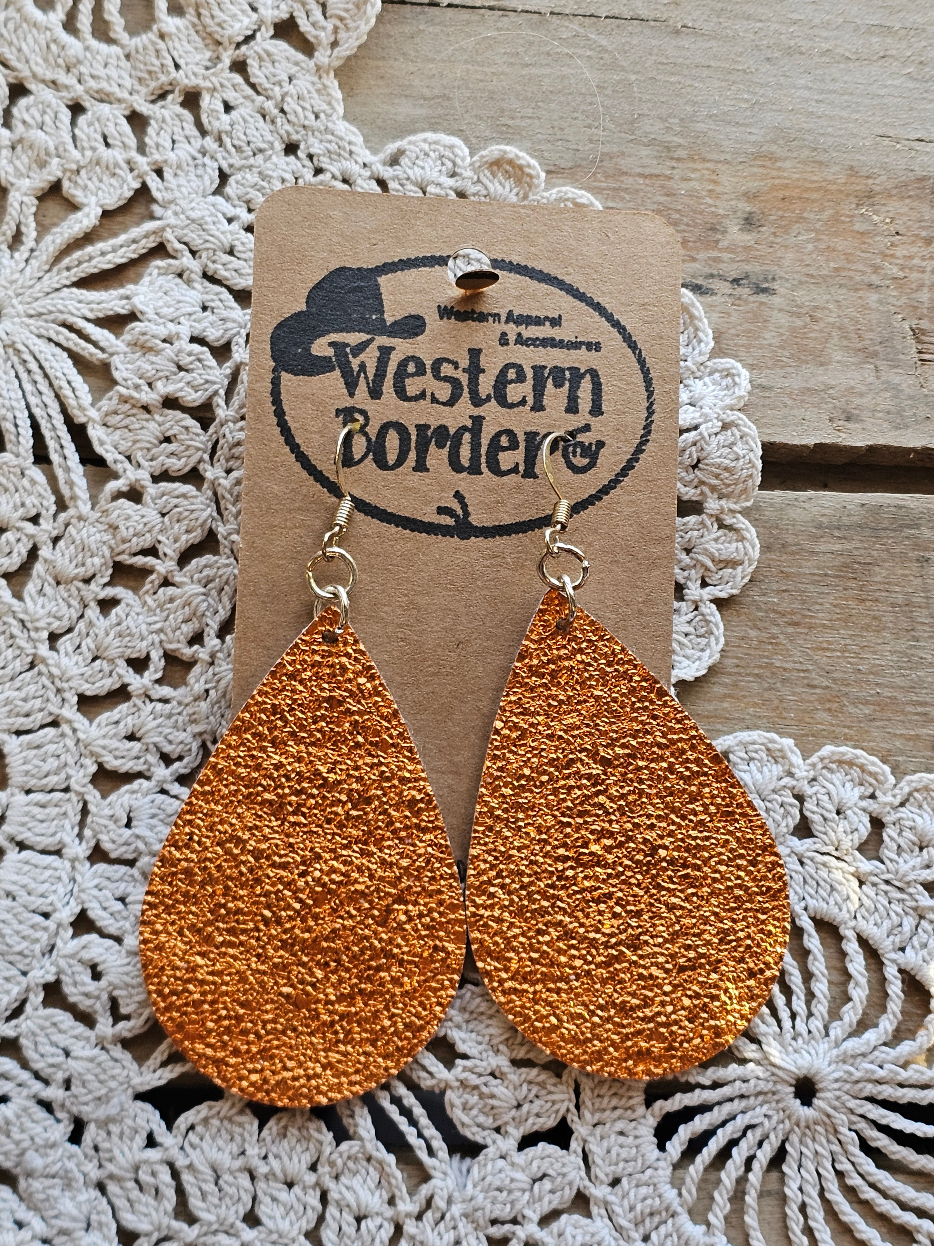 Brown textured teardrop earrings on a 'Western Border' branded card with lace background